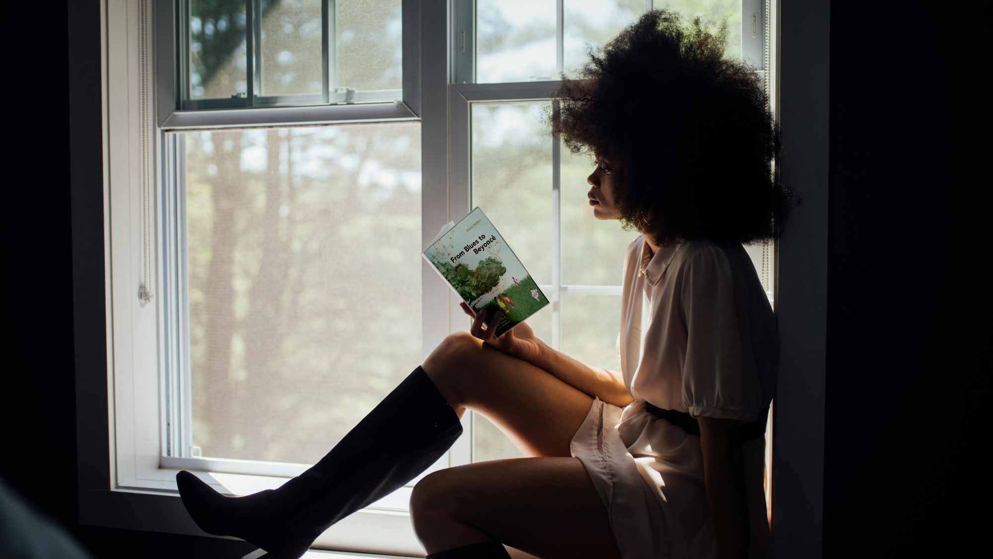 A girl reading a book by the window