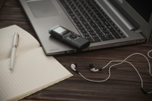 laptop, audio recorder, headphones, pen, and diary of a journalist