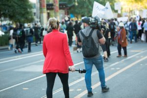 TV news crew live broadcasting a street protest