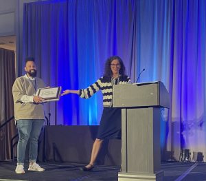 Louis Maraj, standing on the left, receiving a commemorative plaque from Debra Hawhee.