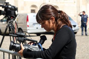 A woman (female-presenting) holding a tv video camera