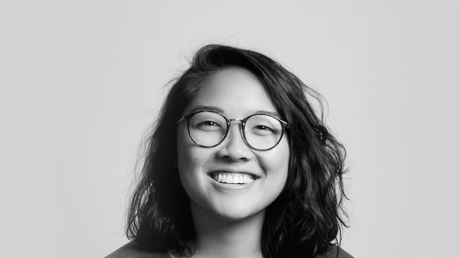 A smiling and bespectacled woman with shoulder-length black hair